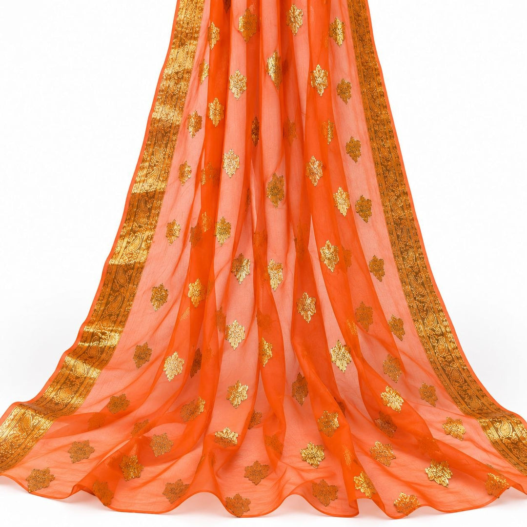 Oransje lurexchiffon med gyllene motiver og guldborter – hengende i myke folder på hvit bakgrunn (bilde 2 av 3)