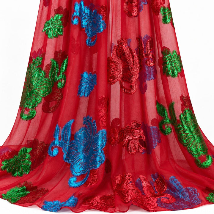 Rød lurex chiffonsilk med fargerike blomstermotiv – hengende i myke folder på hvit bakgrunn (bilde 2 av 3)