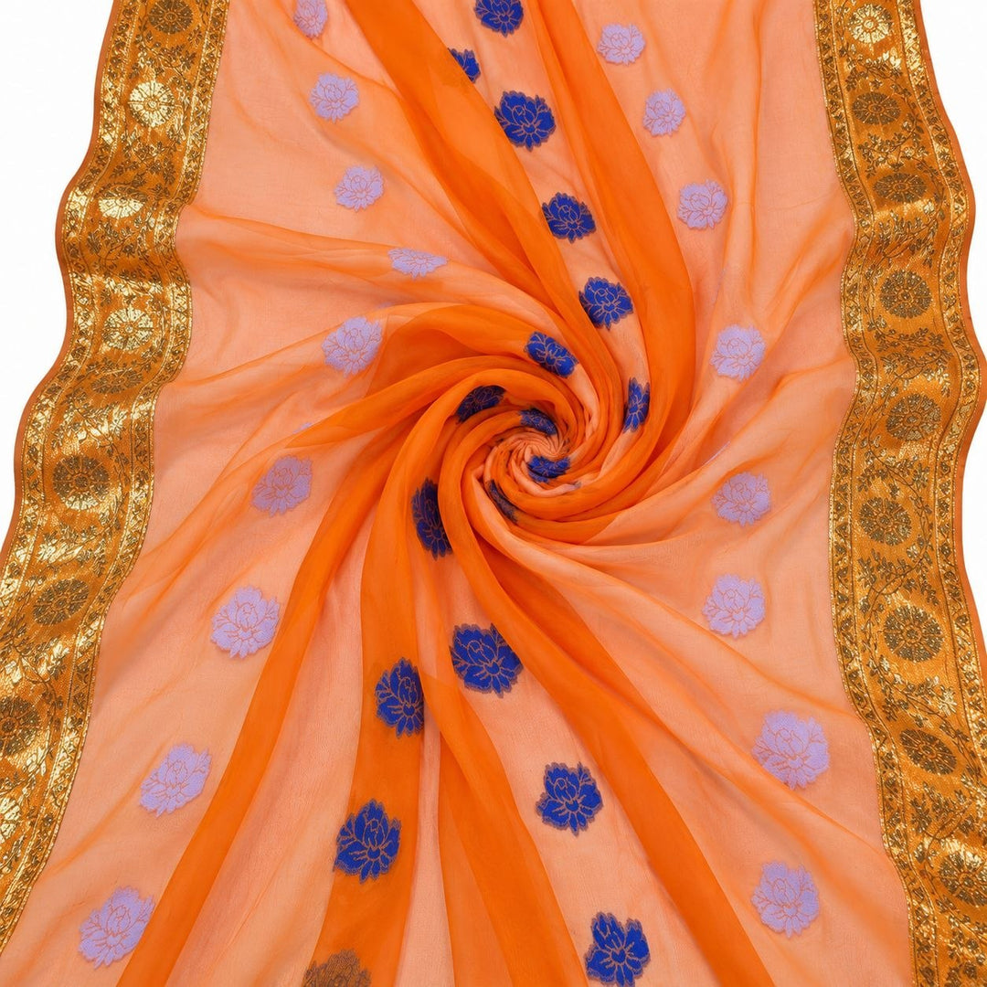 Orange lurex chiffonsilk med blå og lyslilla blomstermotiver og guldborter – stoffet formet som en spiral (bilde 1 av 3)