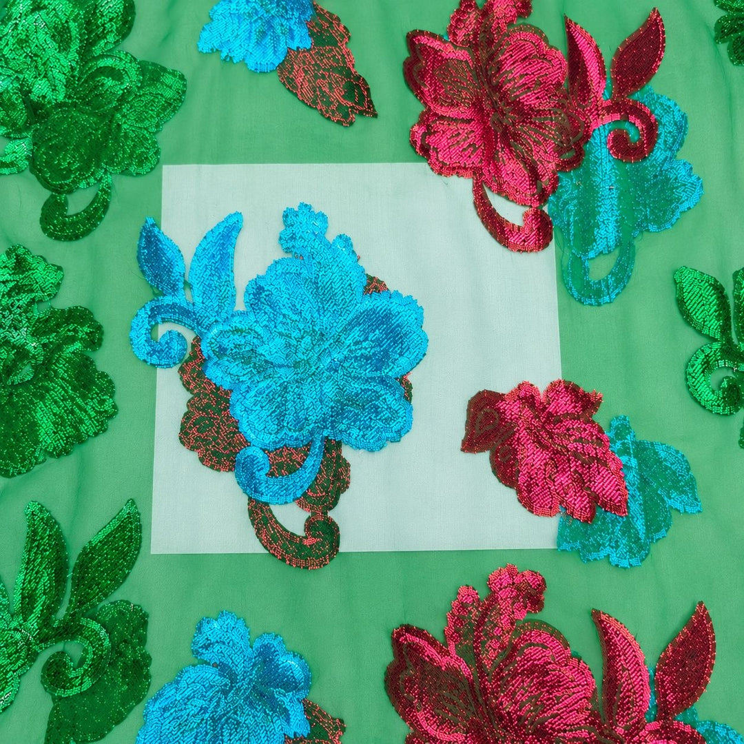 Grønn lurexchiffon – nærbilde av blomstermotivene og stoffets gjennomsiktighet (bilde 3 av 3)