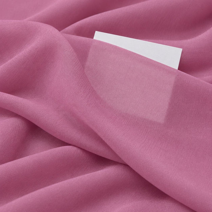 Støvet rosa silkegeorgette – nærbilde med papir bak stoffet som viser at det bare er svakt gjennomsiktig (bilde 3 av 3)